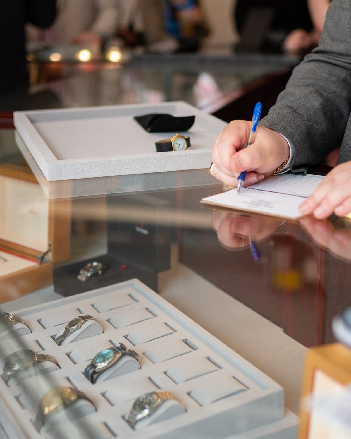 Watch consignment intake at Asbury Park Watches in Asbury Park, NJ — a contract being written at the counter beside trays of consigned watches